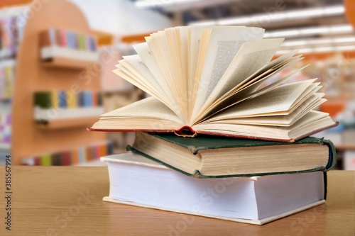 Open book on stack of books with library background.