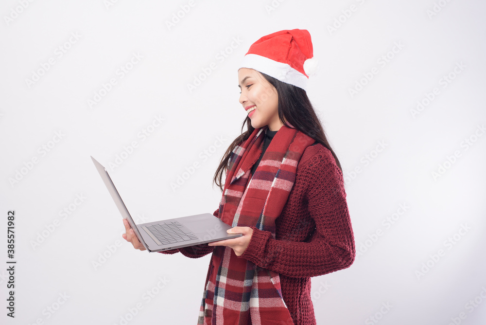 Young smiling woman wearing red Santa Claus hat making video call on social network with family and friends on white background studio. Young smiling woman wearing red Santa Claus hat making video call on social network with family and friends on white background studio.