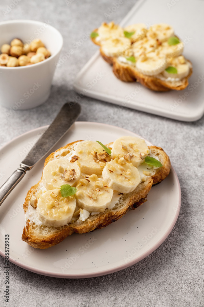 Croissant with banana, honey, nuts and curd cheese on a plate with a vintage knife