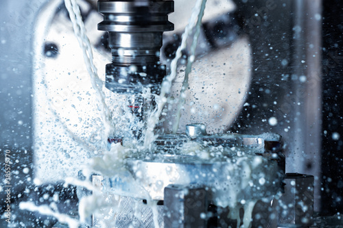 a process of vertical cnc steel milling with external water coolant streams and splashes photo