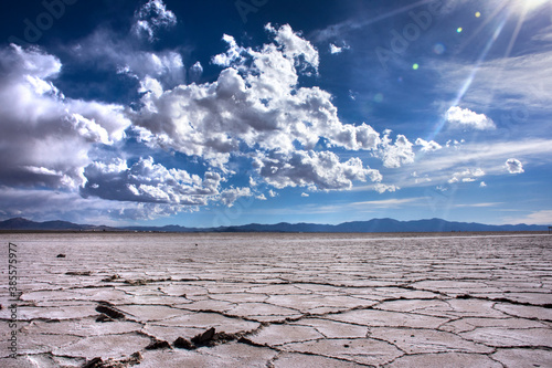 Salar con suelo agrietado y cielo azul con rayos de sol