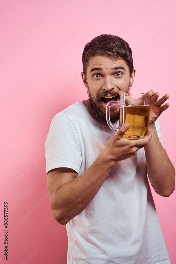 Bearded man with a mug of beer On a pink background fun emotions cropped view of a white T-shirt drunk Bearded man with a mug of beer On a pink background fun emotions cropped view of a white T-shirt drunk