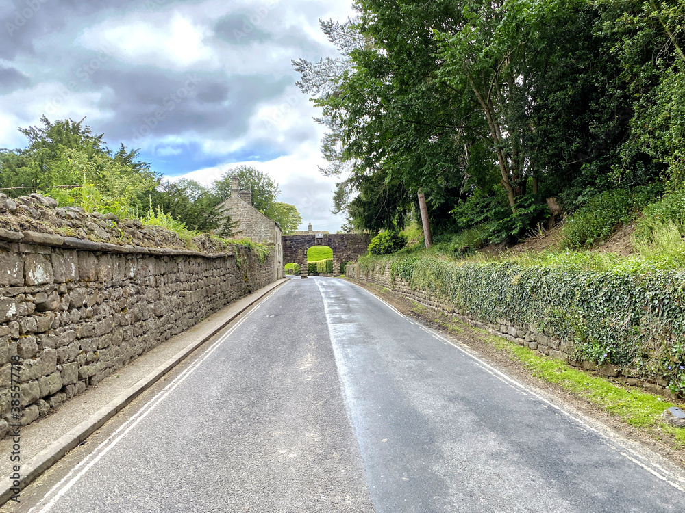 Approaching the Bolton Abbey stone Arch/Aqueduct, with dry stone walls, old trees, on a cloudy day in, Bolton Abbey, Skipton, UK Approaching the Bolton Abbey stone Arch/Aqueduct, with dry stone walls, old trees, on a cloudy day in, Bolton Abbey, Skipton, UK