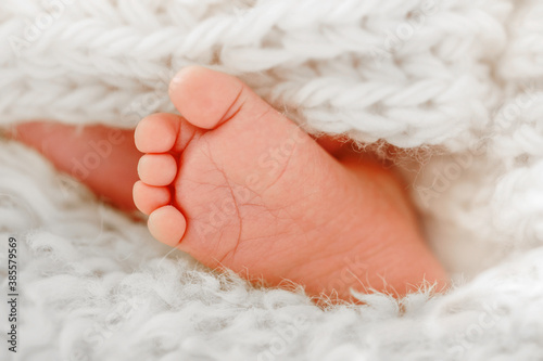 Close up of baby foot on a white knitted woolen blanket. Family concept. Conceptual image of newborn and maternity