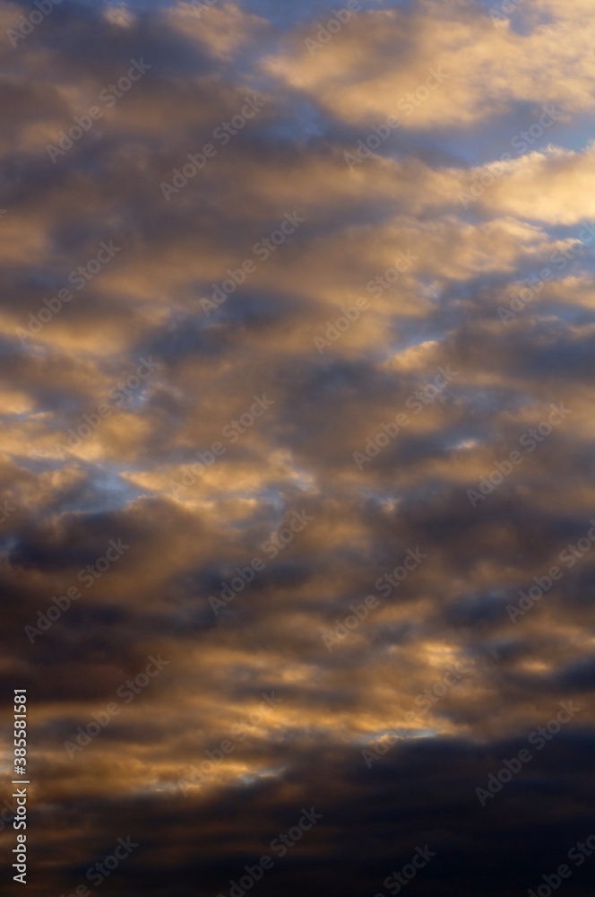Clouds in the blue sky in the evening, during autumn, warm colours - background.