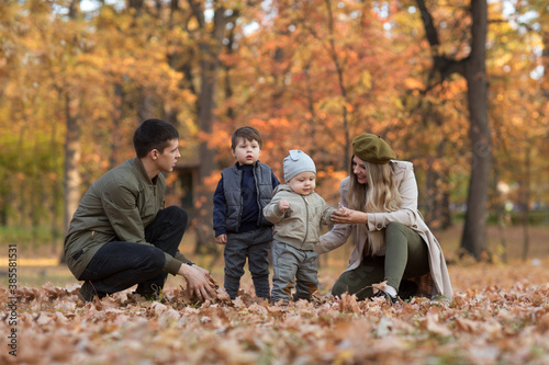happy family Mom, dad and two little kids playing in autumn outdoor.
