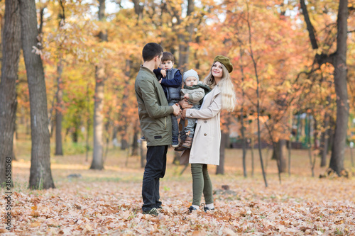 happy family Mom, dad and two little kids playing in autumn outdoor.