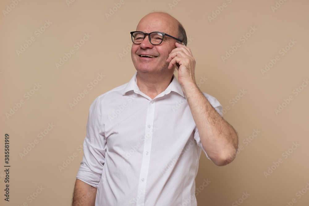 Happy senior man talking on cell phone with his friends. Studio shot Happy senior man talking on cell phone with his friends. Studio shot