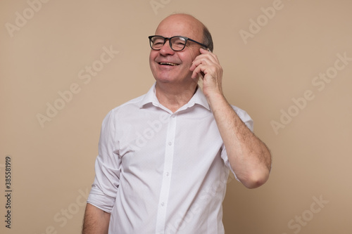 Happy senior man talking on cell phone with his friends. Studio shot