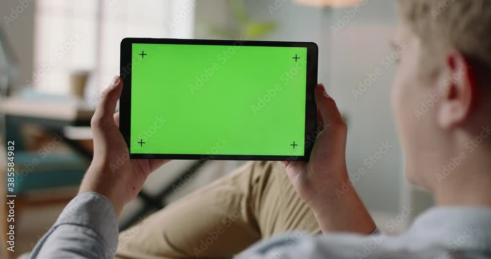 Close up shot of guy using a tablet computer with green mockup screen. Student during online lesson or work conference on self-isolation 4k footage Close up shot of guy using a tablet computer with green mockup screen. Student during online lesson or work conference on self-isolation 4k footage