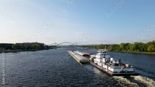 Close up of a bare transporting cargo down the Mississippi river in La Crosse, Wisconsin. Large boat pushing the cargo towards a metal bridge on the river. photo