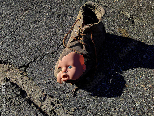 scary and broken doll face with one blue eye along with an old brown boot photo