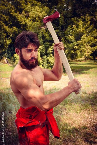 Woodcutter in red coveralls with axe in forest