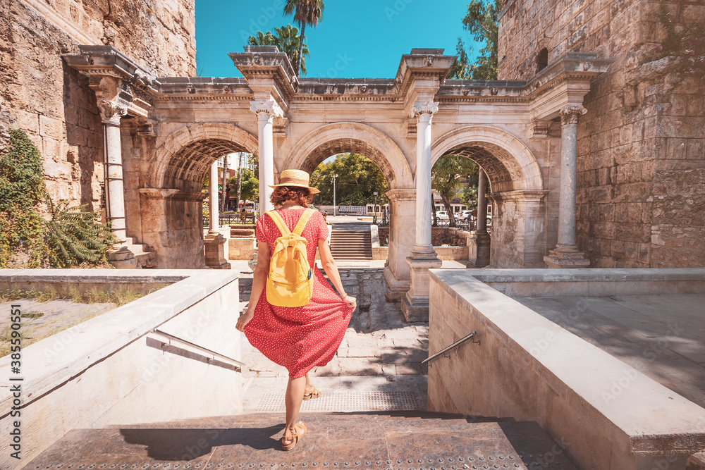 Fototapeta premium Happy female tourist traveler discover interesting places and popular attractions and walks in the old city of Antalya, Turkey. The famous Roman gate of Hadrian