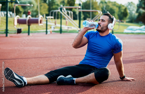 Hydration is important part of exercising. Young man drinking water after training outdoors. Fitness, sport, lifestyle concept