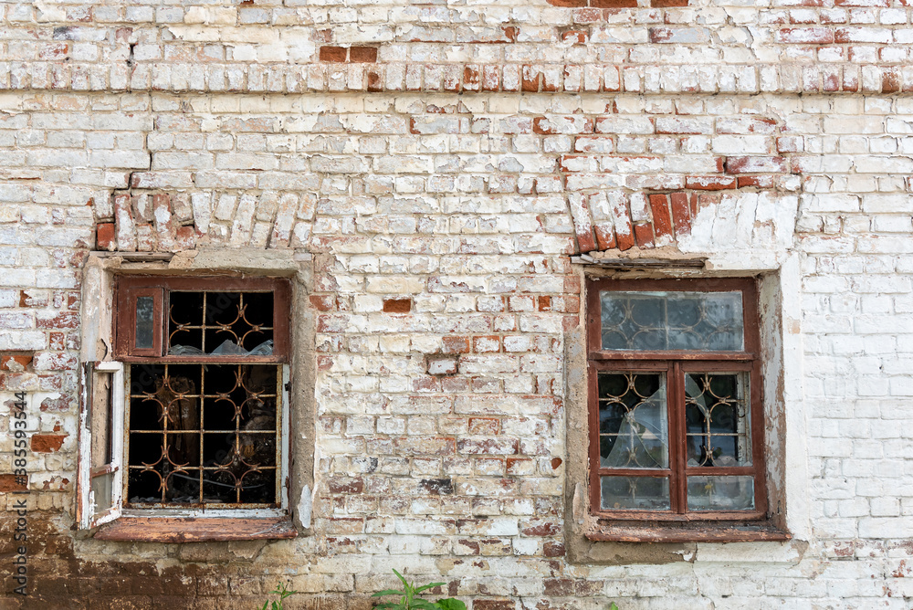 Abandoned or neglected house with damaged dirty brick walls and broken window glass. Weathered dwelling in countryside or poor country. Messy exterior of deserted old building in village or city