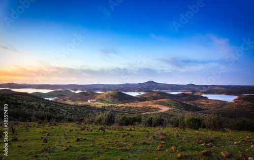 panoramic view of a meadow with a reservoir and mountains in the background