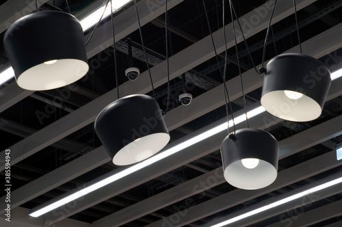 The ceiling is made of gray slats. Large black shades with white bulbs hang from the ceiling