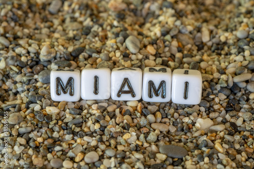 Miami inscription text with name of the vacation destination city in a still life of the letters laid out on a shore sand stones.