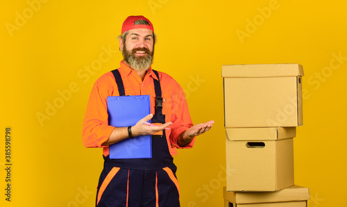 Bearded loader in uniform. Insurance agent. Moving day. Renovation preparation. Unpacking moving boxes. Delivering packages. Bearded man courier hold boxes. Moving to new apartment. Post service © be free