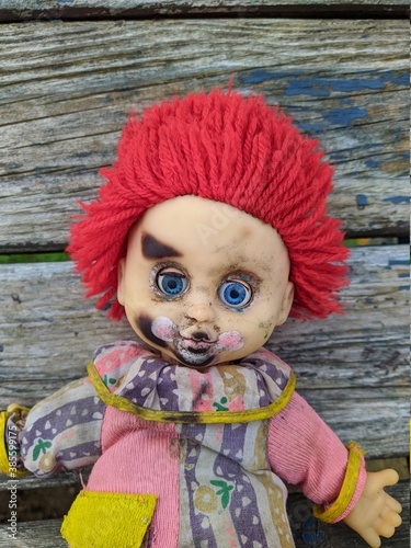 scary toy clown with blue eyes on an old wooden background photo