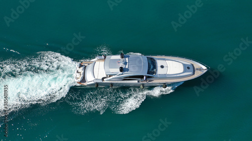 Aerial drone photo of small luxury yacht with wooden deck cruising near tropical exotic port