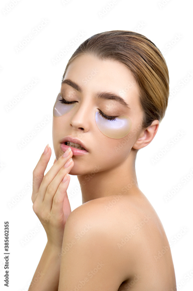 Beautiful young woman applies holographic, moisturizing eye mask, isolated on white. Beautiful young woman applies holographic, moisturizing eye mask, isolated on white.