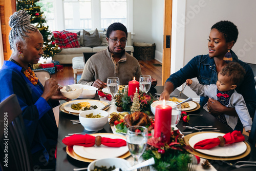 Multigenerational black family eating Christmas dinner together at dining room table photo