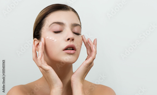 Young woman applying facial gel, peeling or mask on her face. photo