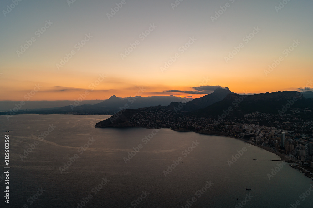 Spectacular sunset with views of the city of Calpe from the Peñon d'Ifach natural park (Alicante, Spain). Photograph taken from a high altitude where you can see the beaches and houses of the city.