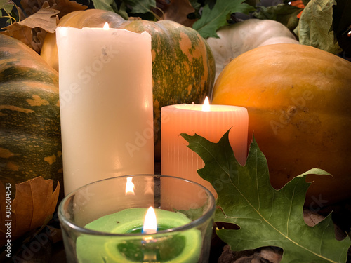 Close up burning candles with orange pumpkins. Autumn Thanksgiving background