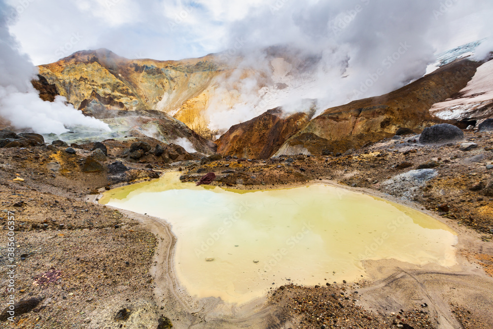 Lake in crater of active volcano. Beautiful dramatic volcanic landscape: hot spring, fumarole, geothermal gas-steam activity. Popular travel destinations for hike, active vacation, mountain climbing.