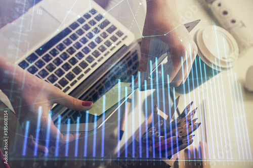 Double exposure of businesswoman hands typing on computer and financial graph hologram drawing. Stock market analysis concept.