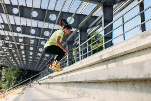 Strong woman doing high jump exercises on steps