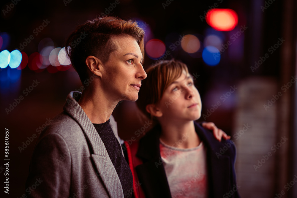 Mother embracing daughter while standing in front of store window