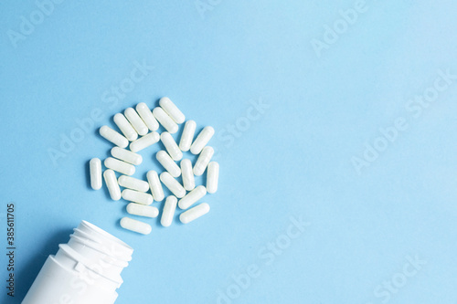 Pharmaceutical medicine pills and capsules with the bottle on blue background and copy space for text.