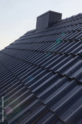 New roof of a detached house with  chimney against the sky. Exterior building design. Roof tiles close up