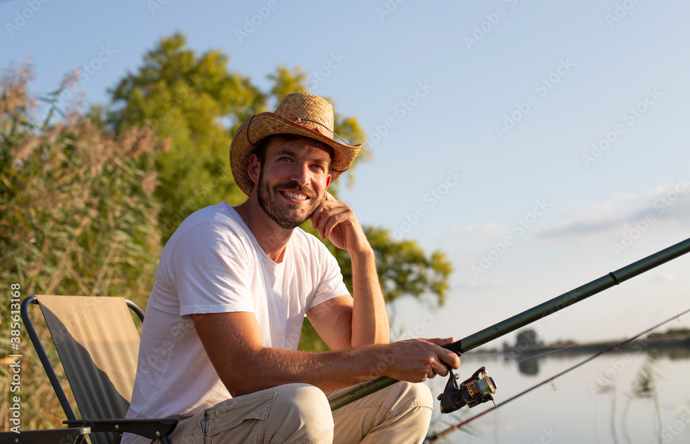 A smiling man is fishing and enjoying the peace at the river.