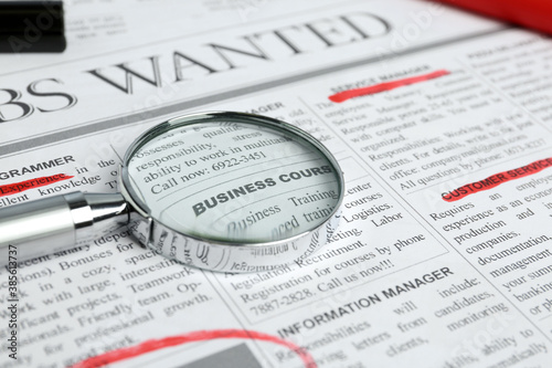 Magnifying glass and marker on newspaper. Job search concept