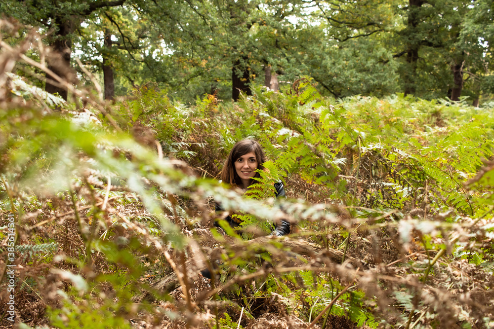 Detail picture of an attractive young female with a black leather jacket located between different bushes Detail picture of an attractive young female with a black leather jacket located between different bushes