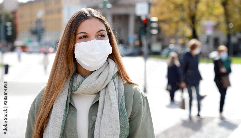 COVID-19 Social Distancing Woman in city street wearing surgical mask against disease virus SARS-CoV-2. Girl with face mask walks respecting social distancing during Pandemic Coronavirus Disease 2019. COVID-19 Social Distancing Woman in city street wearing surgical mask against disease virus SARS-CoV-2. Girl with face mask walks respecting social distancing during Pandemic Coronavirus Disease 2019.