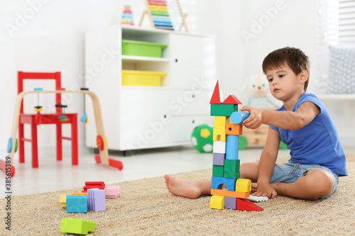 Cute little boy playing with colorful blocks on floor at home. Educational toy