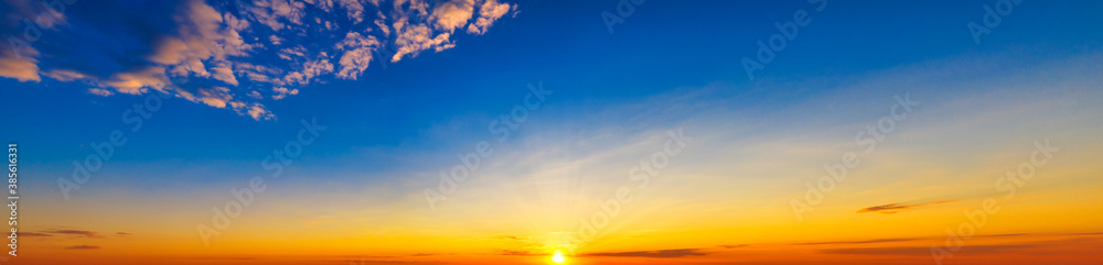 Blue-yellow sky with bright sun at sunset - ultra-wide panorama of the sky for the banner