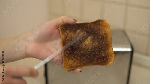 Woman clean the ashes with a burnt toast with a knife. Toasted bread in a toaster