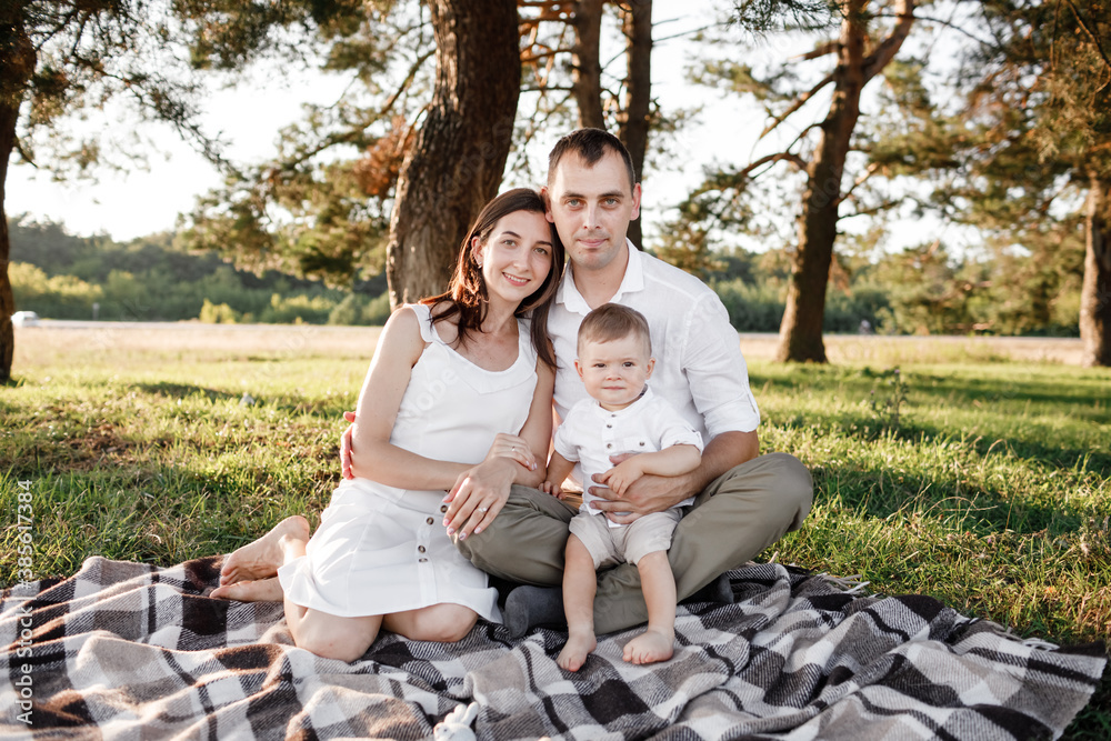 Fototapeta premium happy family mom dad and baby son happy in nature spending time together on summer sunny day. The concept of a fun holiday outdoors. Happy childhood.
