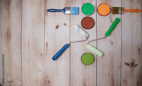 The concept of DIY repair. Paints, brushes and paint rollers are laid out on a wooden background. A place for a space mine. Horizontal orientation