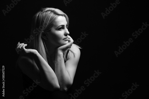 Close-up portrait of beautiful model with long blond hair on black background