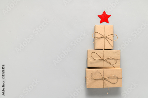 Alternative Christmas tree made from gift boxes with a red star on a light gray background. Place for text, top view.