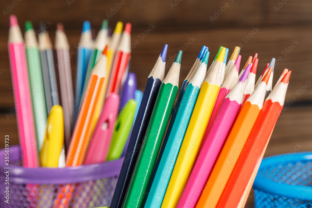 Fototapeta premium Pens and pencils in metal holder in front of wall background