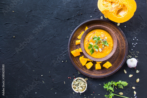 Delicious healthy pumpkin soup, herbs, and ingredients for the dish. Creative atmospheric decoration